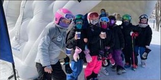 Children in ski gear posing in front of AT&T branded mountain dome